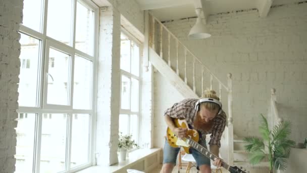 Legrační vousatý muž tanec na posteli zpěvu a hře na elektrickou kytaru v ložnici doma — Stock video