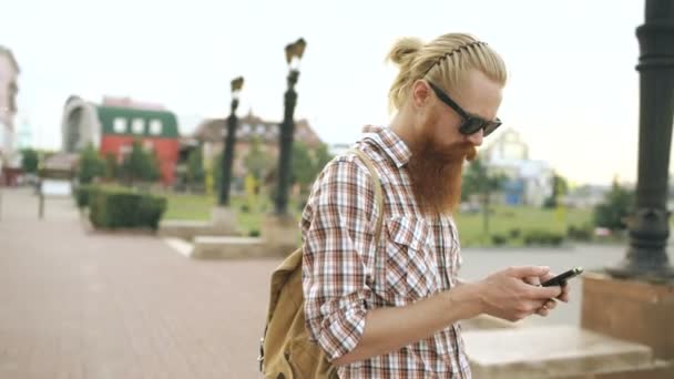 Steadicam-Aufnahme eines bärtigen Touristenmannes, der sich in der Stadt verirrt und per Smartphone-Online-Karte die richtige Wegbeschreibung findet — Stockvideo