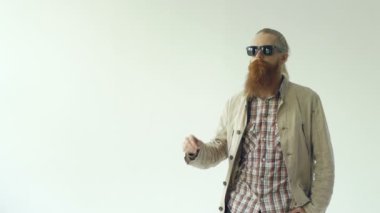 Güneş gözlüğü koy ve beyaz arka plan üzerinde gülümseyen kamera bakarak hipster adam portresi Slowmotion