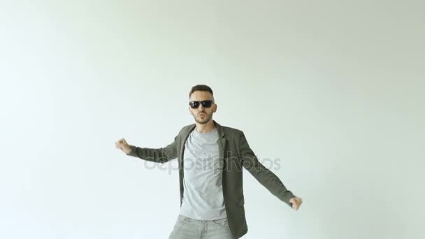 Slowmotion of Young funny man in sunglasses crazy dancing on white background — Stock Video