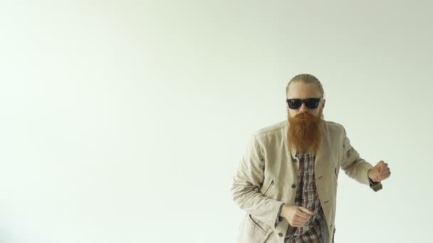 Zeitlupe eines jungen bärtigen Mannes mit Sonnenbrille, der auf weißem Hintergrund tanzt — Stockvideo