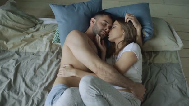 Young beautiful and loving couple kissing on bed in the morning — Stock Video