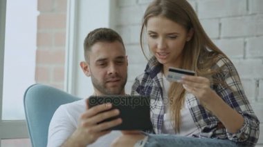 Online alışveriş için dijital tablet bilgisayar kullanarak genç çift modern loft daire balkonda oturup