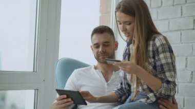 Online alışveriş için dijital tablet bilgisayar kullanarak genç çift modern loft daire balkonda oturup