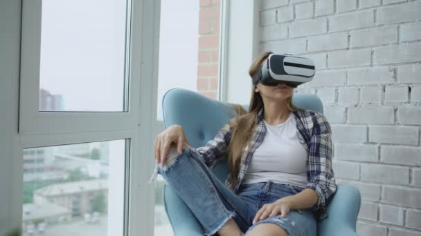 Mladá žena se Vr zkušenosti s používáním soupravu pro virtuální realitu sedí v křesle na balkóně — Stock video