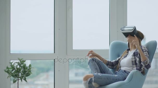 Mujer joven tiene experiencia VR utilizando auriculares de realidad virtual sentado en la silla en el balcón — Vídeo de stock