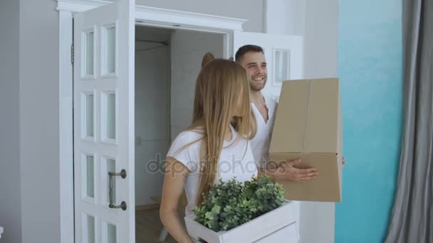 Joven feliz pareja primera vez caminando en nueva casa después de mudarse y besarse — Vídeos de Stock