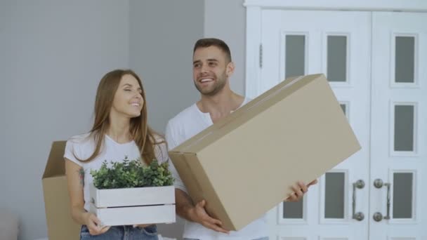 Glückliches Paar, das aufgeregt ihrem neuen Zuhause zusieht. junge Frau gibt ihrem Freund Schlüssel und küsst ihn — Stockvideo