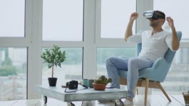 Loft daire balkon sandalyede oturan sanal gerçeklik kulaklık kullanarak Vr deneyimi var genç adam