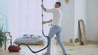 Genç adam eğleniyor kadınla dans gibi elektrikli süpürge ile temizlik evi