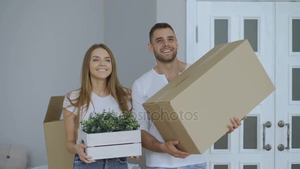 Glückliches Paar, das aufgeregt ihrem neuen Zuhause zusieht. junge Frau gibt ihrem Freund Schlüssel und küsst ihn — Stockvideo