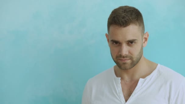 Retrato del joven sonriendo a la cámara y coqueteando sobre el concepto de fondo azul — Vídeos de Stock