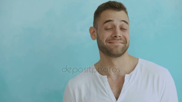 Portret van de jonge knappe man grimassen in camera en Toon verschillende emoties op blauwe achtergrond — Stockvideo