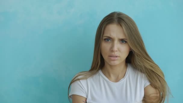 Portret van boze jonge vrouw op zoek naar camera nerveus op blauwe achtergrond — Stockvideo