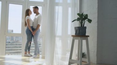 Penceresinde yeni evlerinin yakınındaki öpüşme ang kucaklayan genç mutlu çift