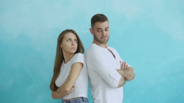 Молодая пара расстроена и сердится друг на друга стоя сзади на синем фоне — стоковое видео