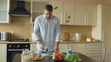 Yakışıklı genç adam kesme sebze salatası evde mutfak için vejetaryen kahvaltı yemek