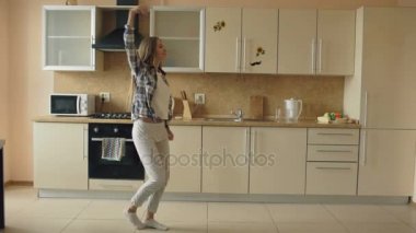 Dans ve kepçe ile evde mutfakta boş zamanlarınızı yaparken şarkı neşeli genç komik kadın