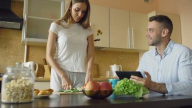 Sabah mutfakta sohbet çekici çift. Güzel bir kadın kocası kahvaltı yemek yaparken besleme