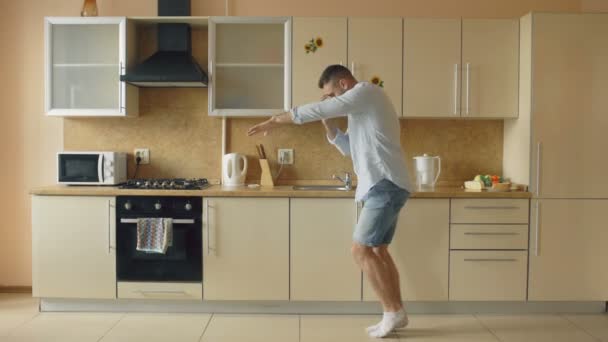 Knappe jonge grappig man in de keuken thuis in de ochtend dansen en hebben plezier op vakantie — Stockvideo