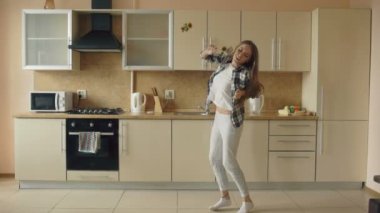 Dans ve kepçe ile evde mutfakta boş zamanlarınızı yaparken şarkı neşeli genç komik kadın