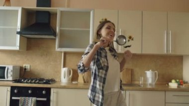 Dans ve kepçe ile evde mutfakta boş zamanlarınızı yaparken şarkı neşeli genç komik kadın