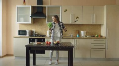 Dans ve marul mikrofon ile kahvaltı yemek yaparken şarkı neşeli genç komik kadın