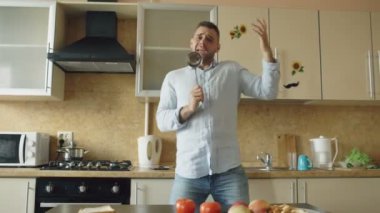 Dans ve kepçe ile evde mutfakta yemek yaparken şarkı çekici genç komik adam