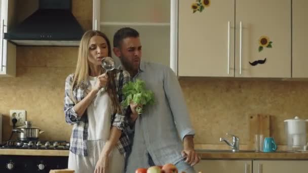 Attraente giovane coppia gioiosa divertirsi ballando e cantando mentre si cucina in cucina a casa — Video Stock