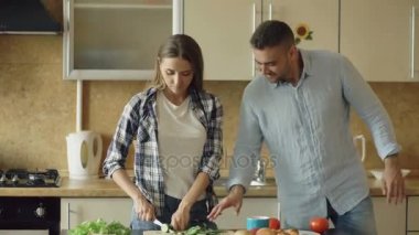 Mutlu genç çift mutfakta. Çekici kadın yemek kahvaltı ve tat gıda için isteyen erkek arkadaşı kelepçe