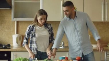 Mutlu genç çift mutfakta. Çekici kadın yemek kahvaltı ve tat gıda için isteyen erkek arkadaşı kelepçe