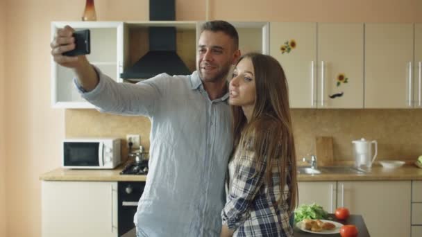 Jonge gelukkige paar met online video-chat in de keuken thuis — Stockvideo