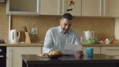 Ağır çekim yakışıklı adamın mutfakta okuyarak iyi haber almak süre evde kahvaltı var