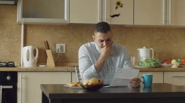 Kızgın genç adam evde mutfakta ödenmemiş fatura ile mektup okuma yavaş hareket
