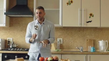 Yavaş bir dans ve kepçe ile evde mutfakta yemek yaparken şarkı çekici genç komik adam