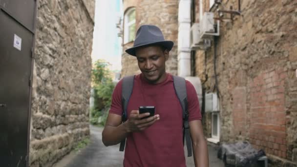 Steadicam colpo di felice turista uomo a piedi e guardando la guida della città nel suo smartphone per trovare le indicazioni per il luogo famoso — Video Stock