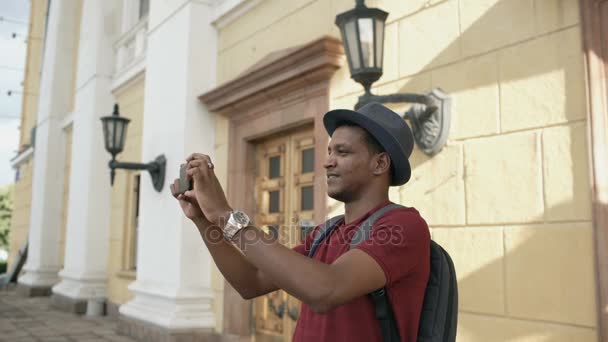 Carrera mixta feliz turista tomando fotos en su cámara de teléfono inteligente de pie cerca del famoso edificio en Europa — Vídeo de stock