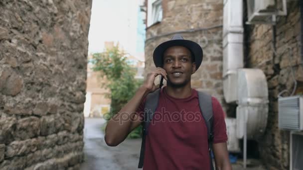 Steadicam disparó al turista afroamericano caminando y hablando por teléfono. Joven hombre feliz viajando por Europa — Vídeo de stock