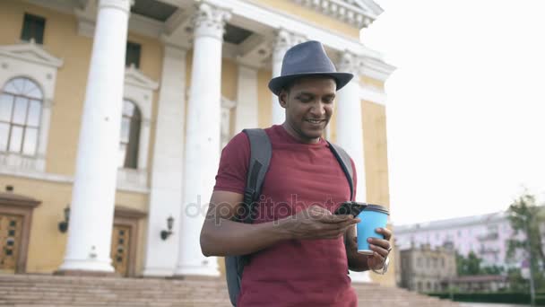 Steadicam tiro de homem turista sorridente navegando seu smartphone perto de lugar histórico famoso na Europa — Vídeo de Stock