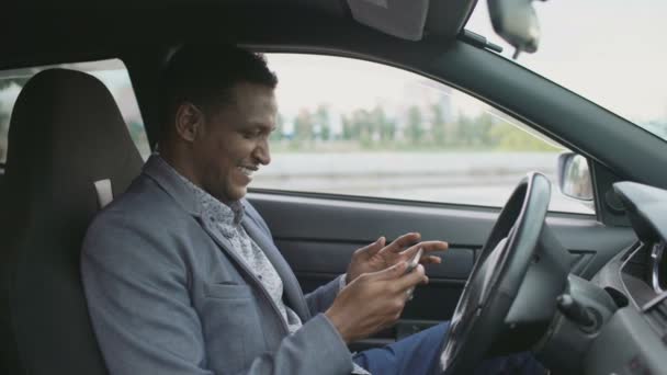 Feliz hombre de negocios afroamericano surfeando en las redes sociales en su tableta de ordenador sentado dentro de su coche — Vídeos de Stock