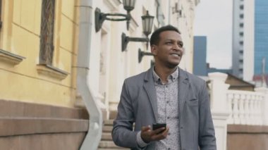 Yavaş hareket smartphone kullanarak ve sokak açık havada arıyorum genç mutlu iş adamı