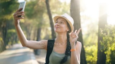 Selfie akıllı telefon fotoğraf makinesi ile seyahat ve otostop sırasında çekim şapkalı komik turist kız