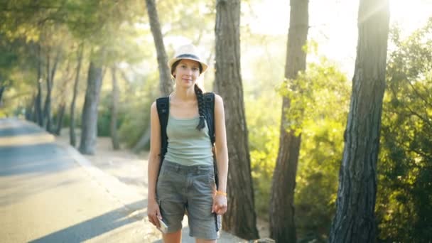 Retrato de menina turística atraente sorrindo e olhando para a câmera enquanto caminha e caminhadas bela floresta — Vídeo de Stock