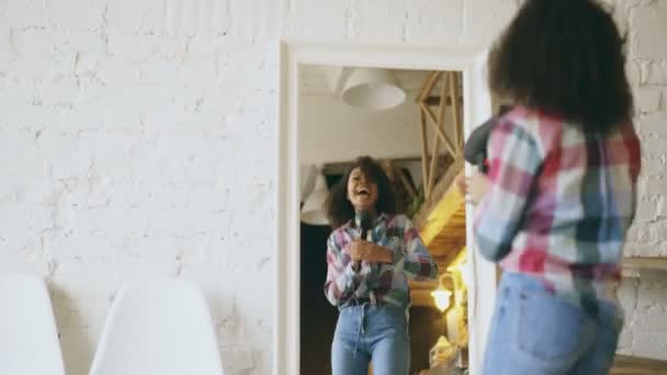 Lockig rolig amerikansk flicka dans och sång med hårtork som framför spegeln hemma — Stockvideo