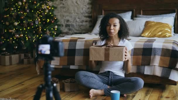 Ung lockigt blandad ras kvinna inspelning video blogg om förpackning presentkartong jul hemma — Stockvideo