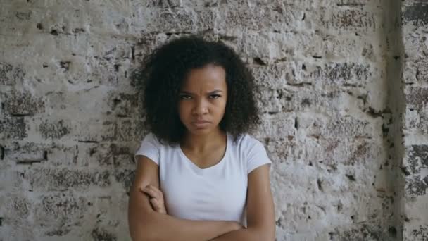 Portrait of angry curly mixed race woman looking into camera nervous on brick wall background — Stock Video