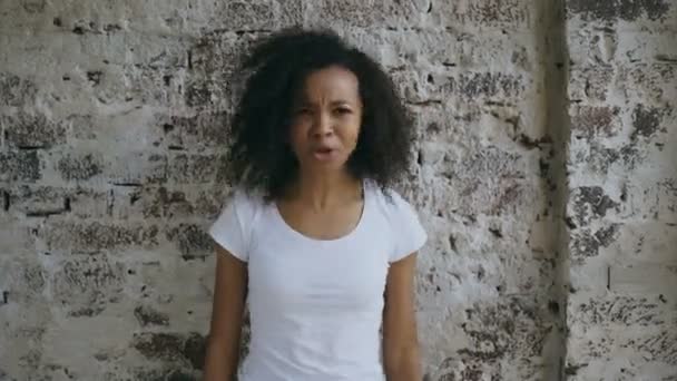 Angry curly african american woman very upset and screaming looking into camera on brick wall background — Stock Video