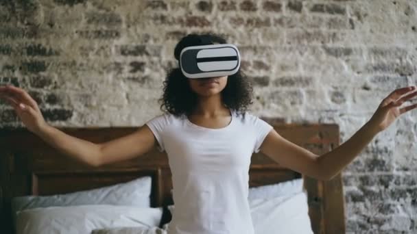 Jovem menina de raça mista recebendo experiência usando óculos VR 360 de realidade virtual em casa — Vídeo de Stock