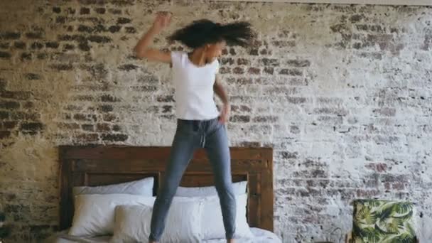 Curly mixte race jeune fille joyeuse ont plaisir à danser sur le lit à la maison — Video