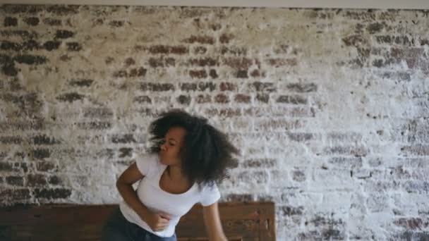 Krullend Afro-Amerikaanse jonge vrolijke meisje veel plezier dansen op bed thuis — Stockvideo